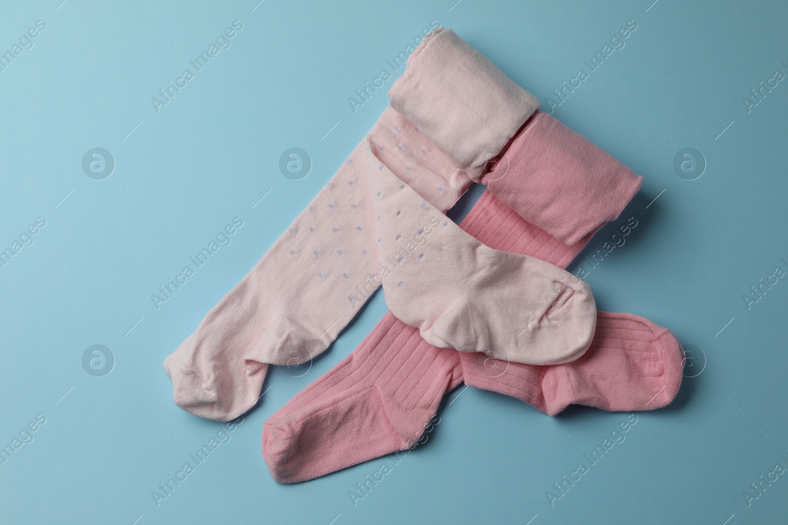 Photo of Pink child's tights on light blue background, top view