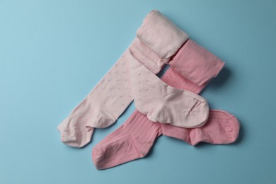 Photo of Pink child's tights on light blue background, top view