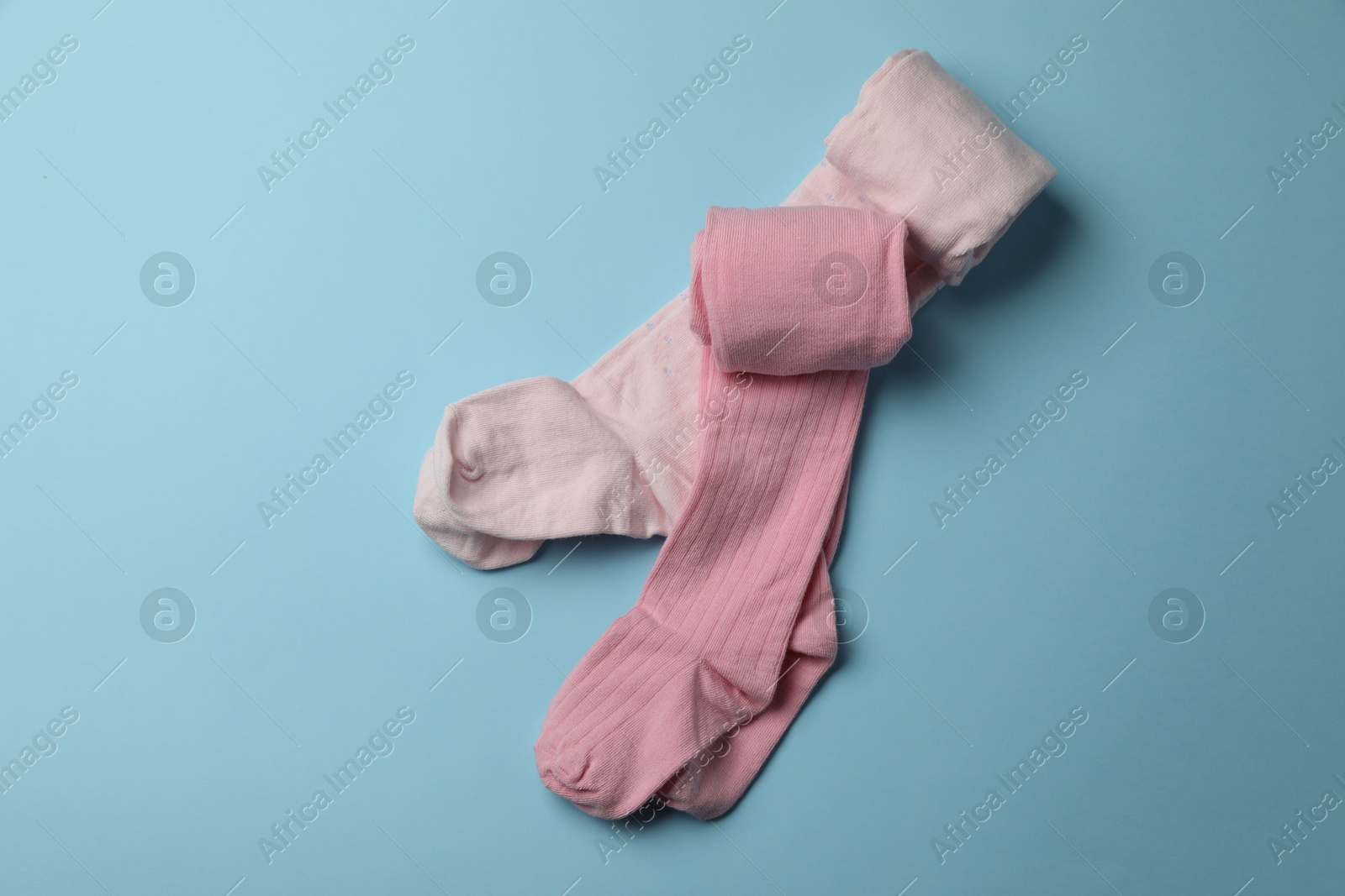 Photo of Pink child's tights on light blue background, top view