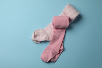 Photo of Pink child's tights on light blue background, top view