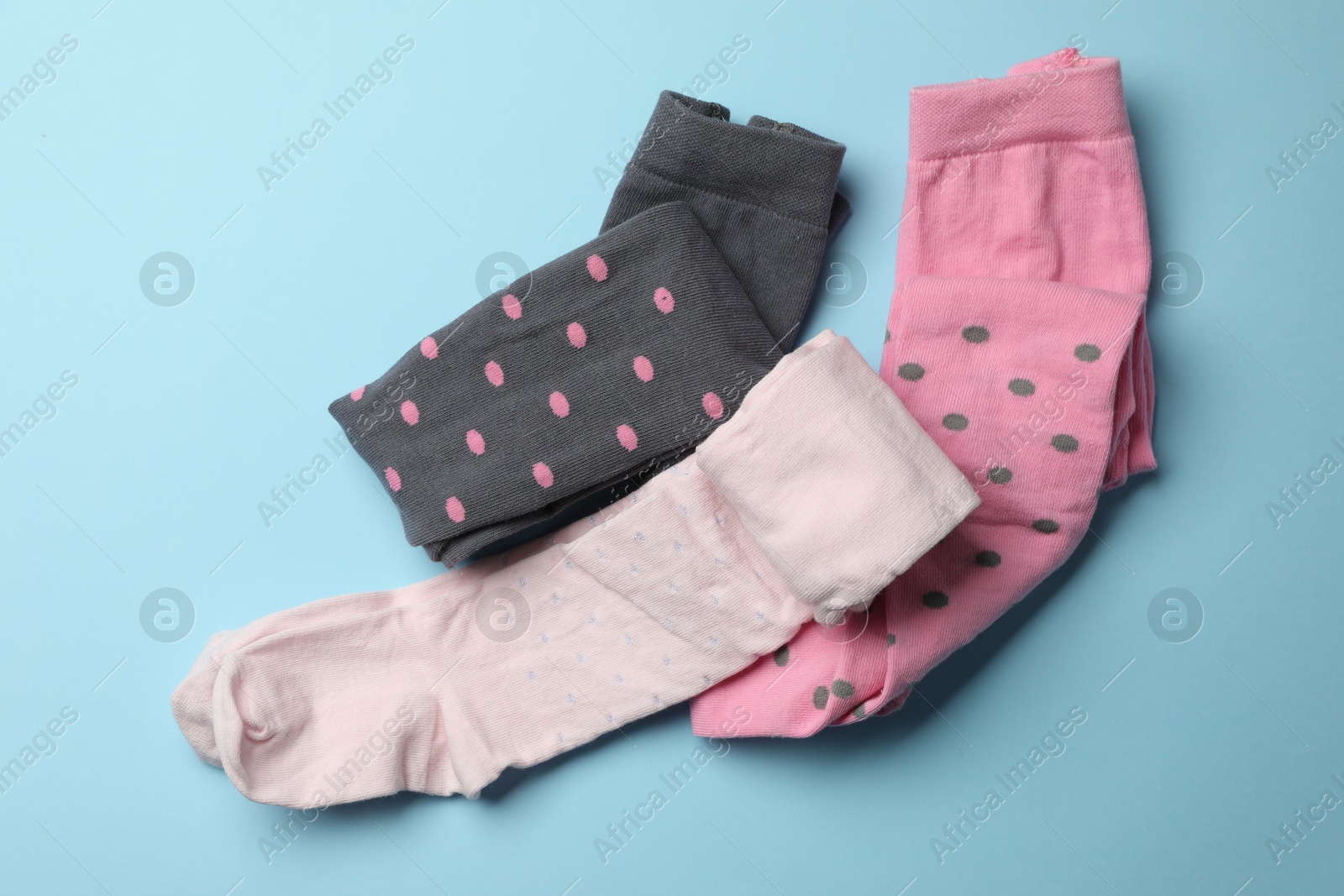 Photo of Different child's tights on light blue background, flat lay