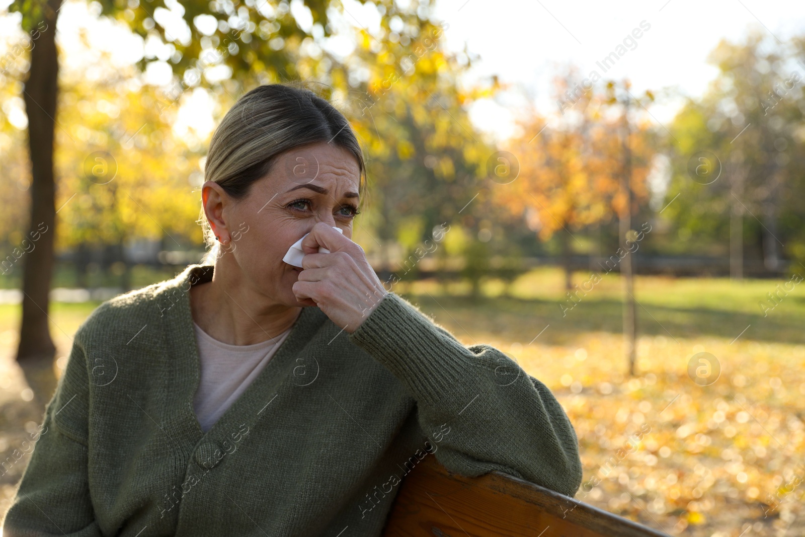 Photo of Woman with runny nose in park, space for text