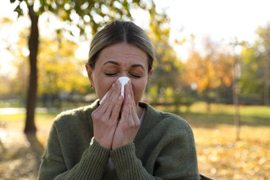 Photo of Woman with tissue blowing runny nose in park