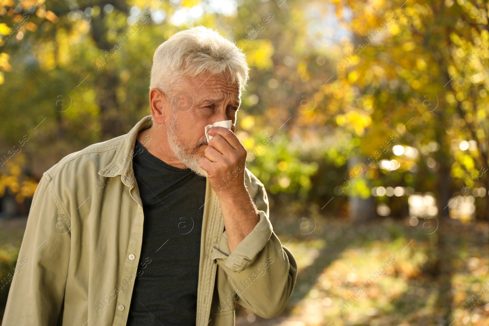 Photo of Senior man with runny nose in park, space for text