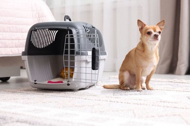 Photo of Adorable dog and pet carrier on floor indoors