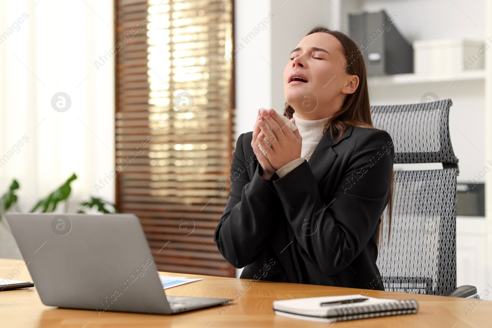 Photo of Sick woman with runny nose at table in office