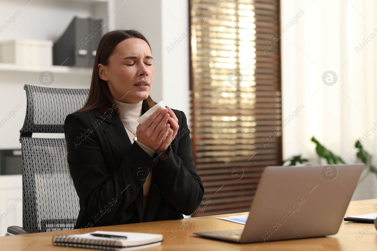 Photo of Sick woman with runny nose at table in office