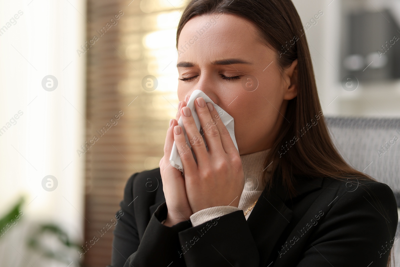 Photo of Sick woman with runny nose in office, space for text