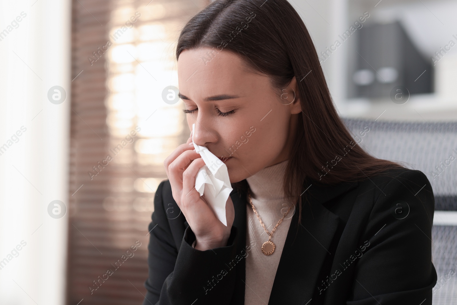 Photo of Sick woman with runny nose in office, space for text