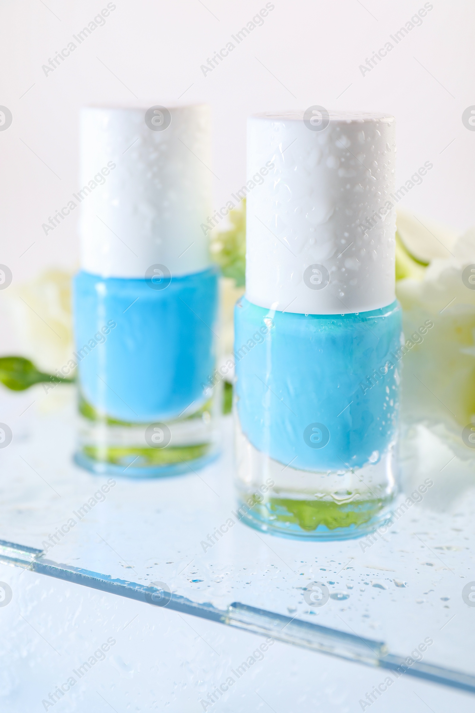 Photo of Nail polishes in bottles on mirror surface, closeup