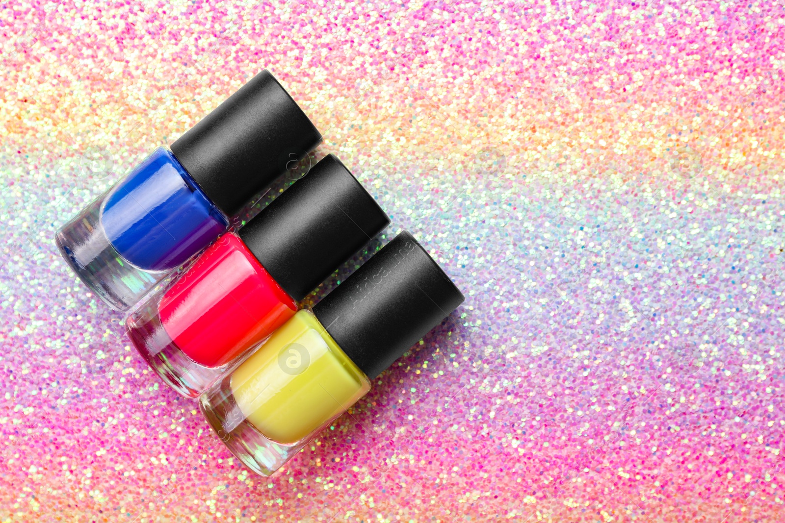 Photo of Nail polishes in bottles on bright textured background, flat lay. Space for text