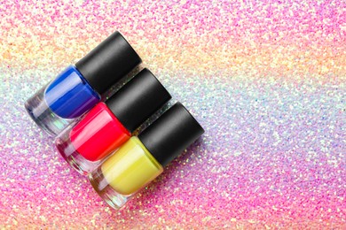 Nail polishes in bottles on bright textured background, flat lay. Space for text