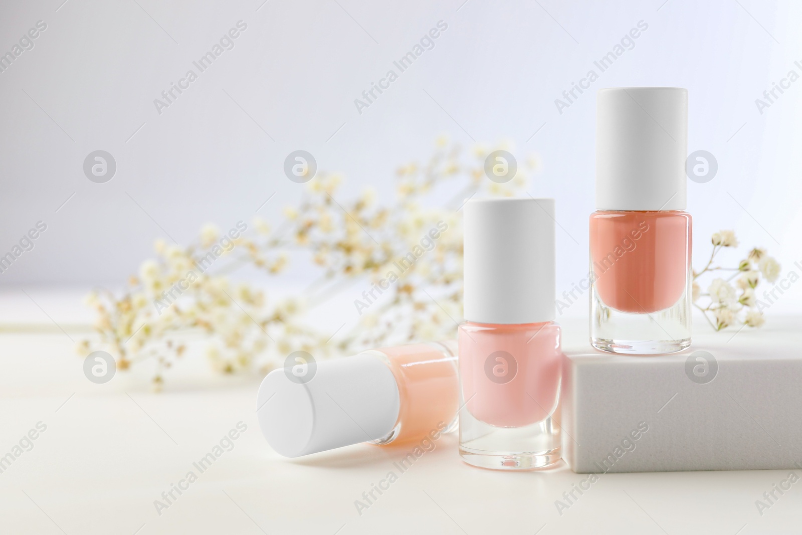 Photo of Nail polishes in bottles on white table, space for text