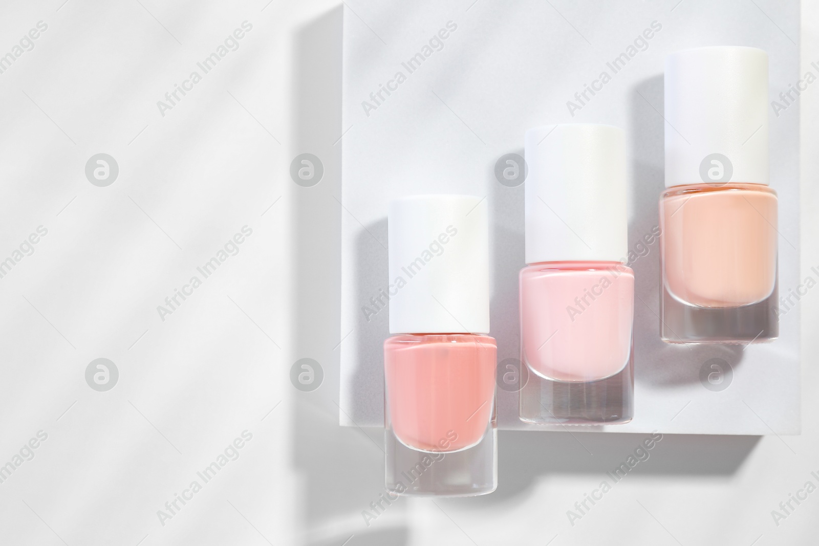 Photo of Nail polishes in bottles on white background, flat lay. Space for text