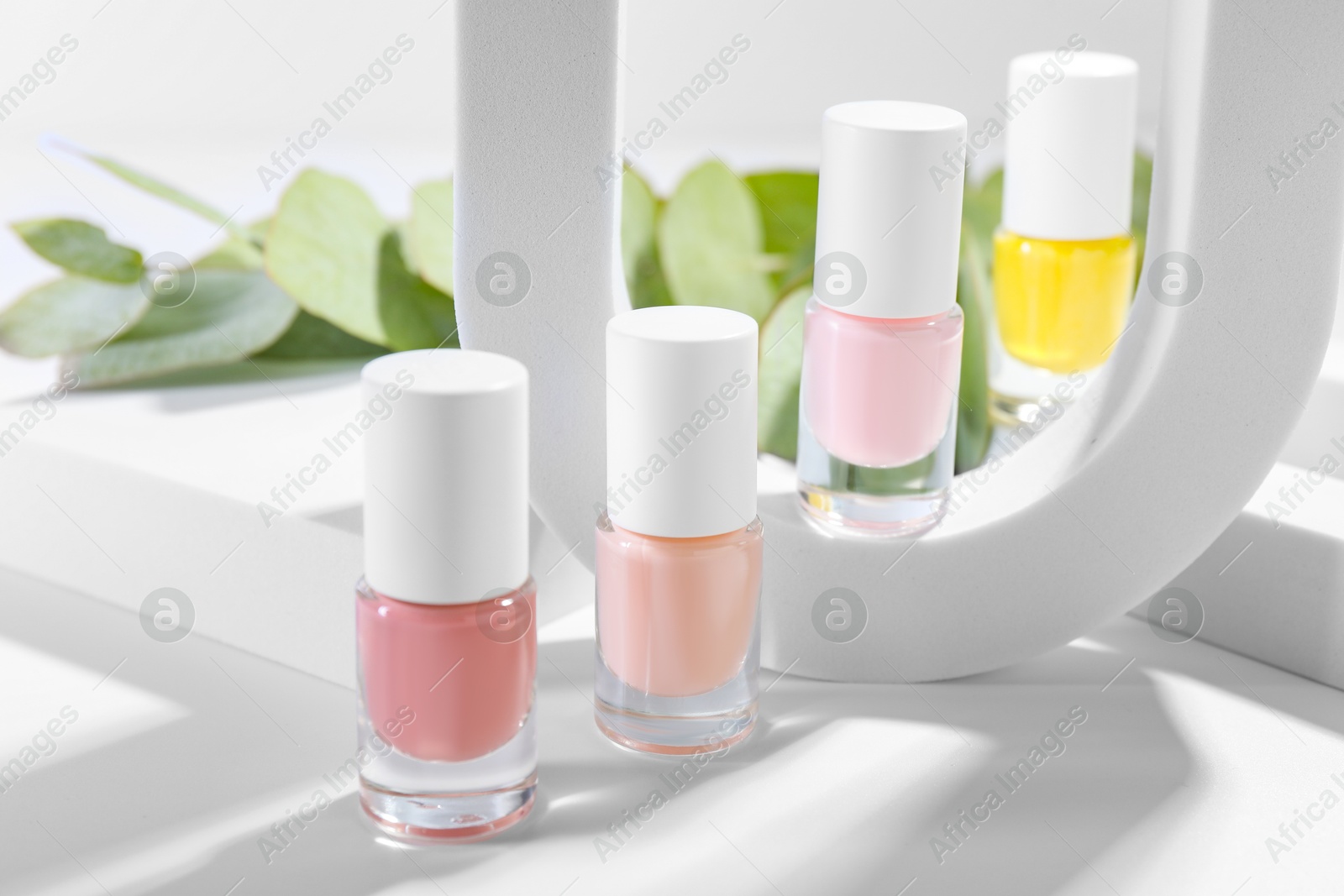 Photo of Stylish presentation of nail polishes in bottles on white table