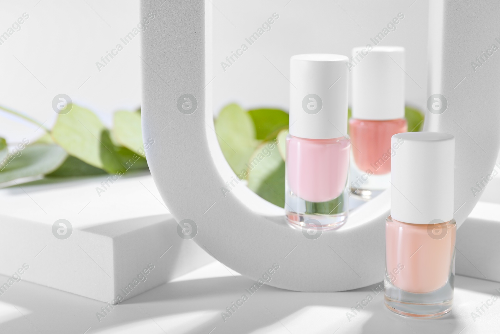 Photo of Stylish presentation of nail polishes in bottles on white table