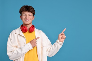 Photo of Happy teenage boy with headphones on light blue background, space for text