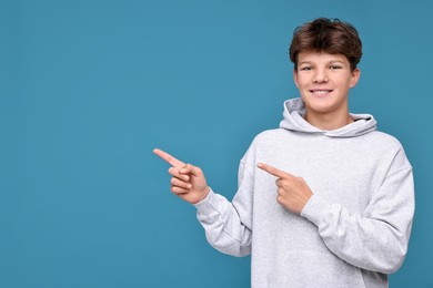 Photo of Portrait of happy teenage boy on light blue background, space for text