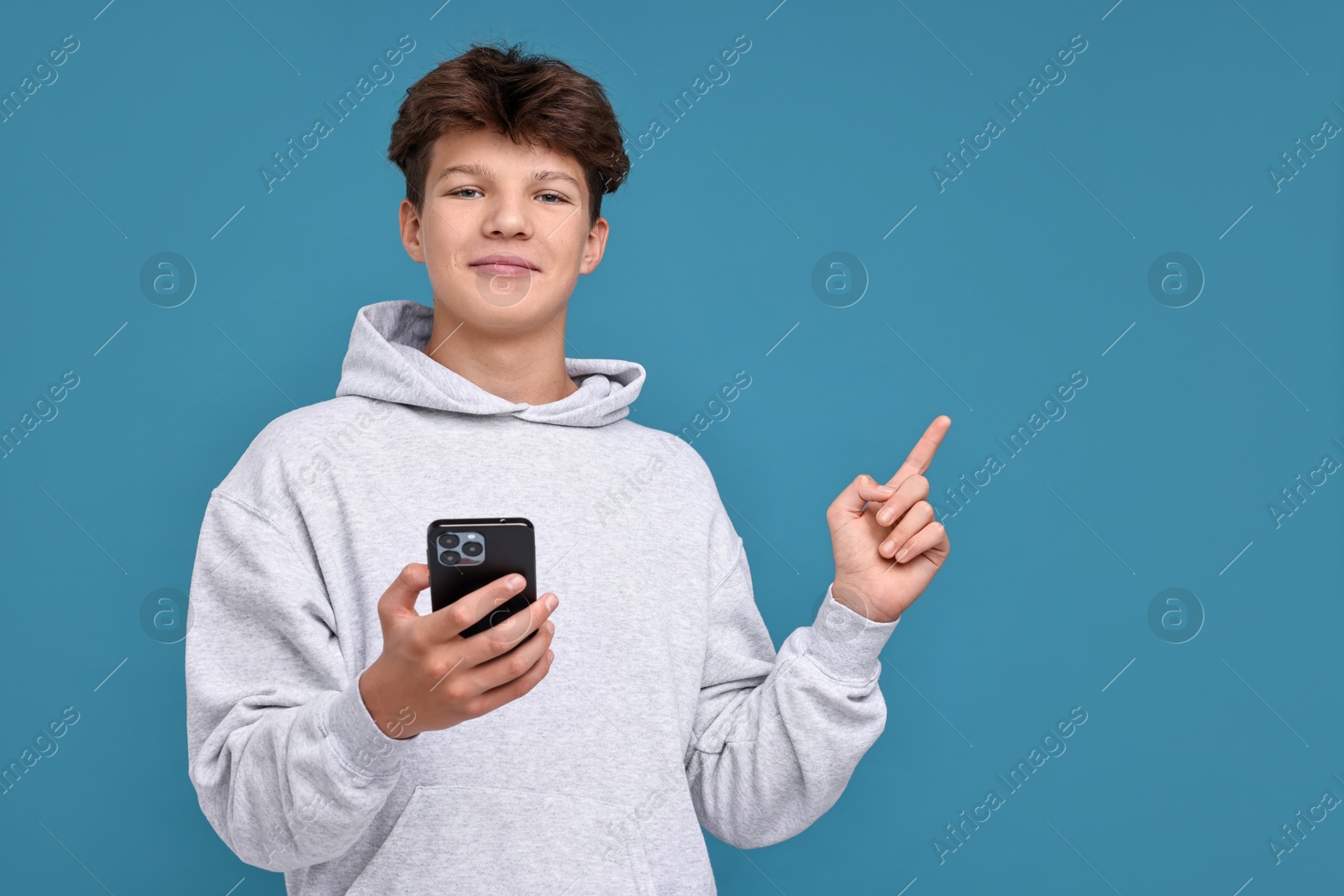 Photo of Teenage boy with smartphone on light blue background, space for text