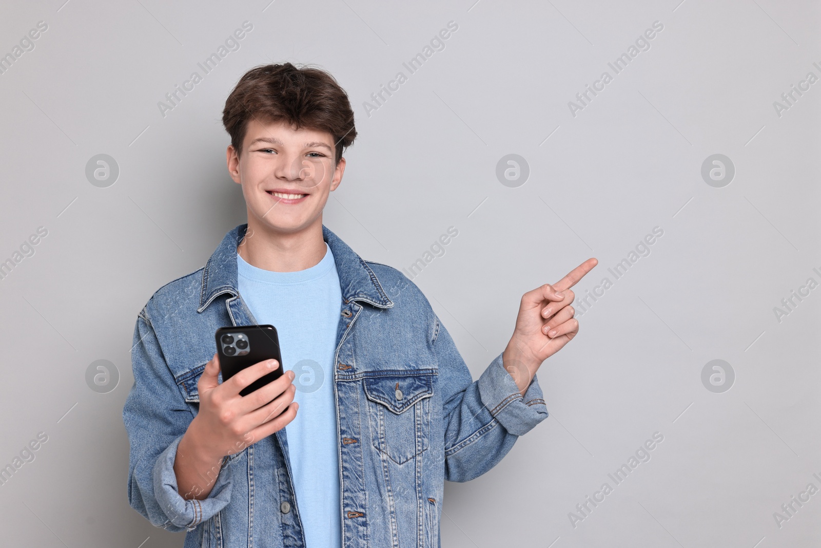 Photo of Teenage boy with smartphone on light grey background, space for text