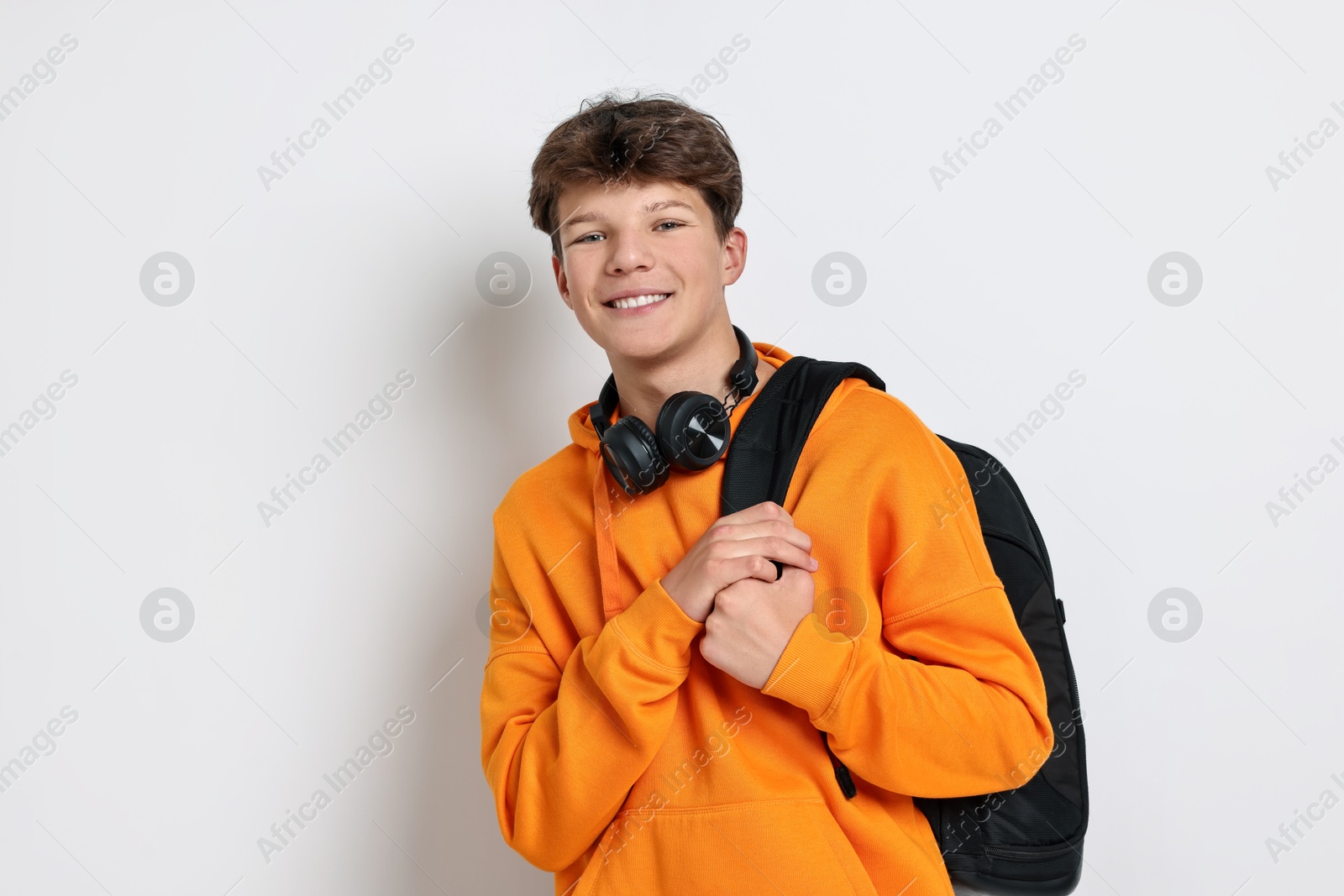 Photo of Teenage boy with headphones and backpack on white background