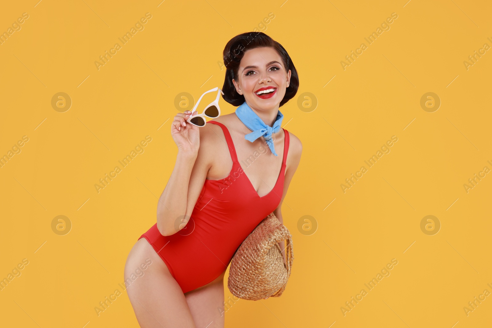 Photo of Pin-up woman in swimsuit with beach bag on orange background