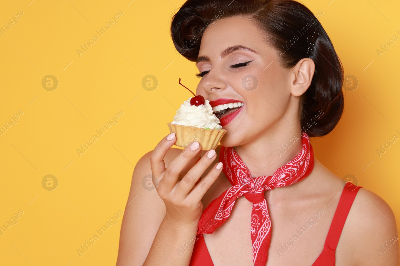 Photo of Pin-up woman eating cupcake on orange background