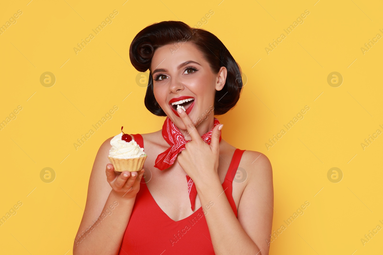 Photo of Pin-up woman eating cupcake on orange background