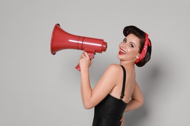 Photo of Pin-up woman with megaphone speaker on grey background