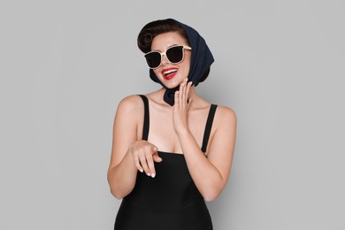 Pin-up woman in sunglasses on grey background