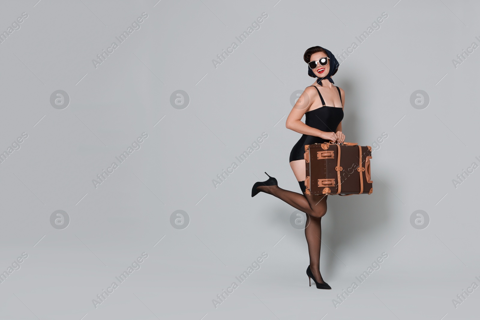 Photo of Pin-up woman with suitcase on grey background