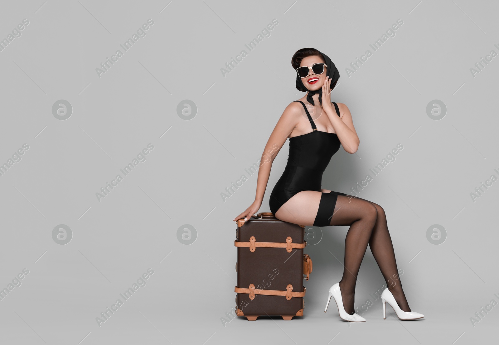 Photo of Pin-up woman with suitcase on grey background, space for text