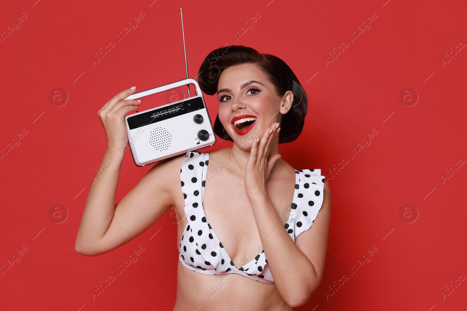 Photo of Pin-up woman in bikini with radio receiver on red background