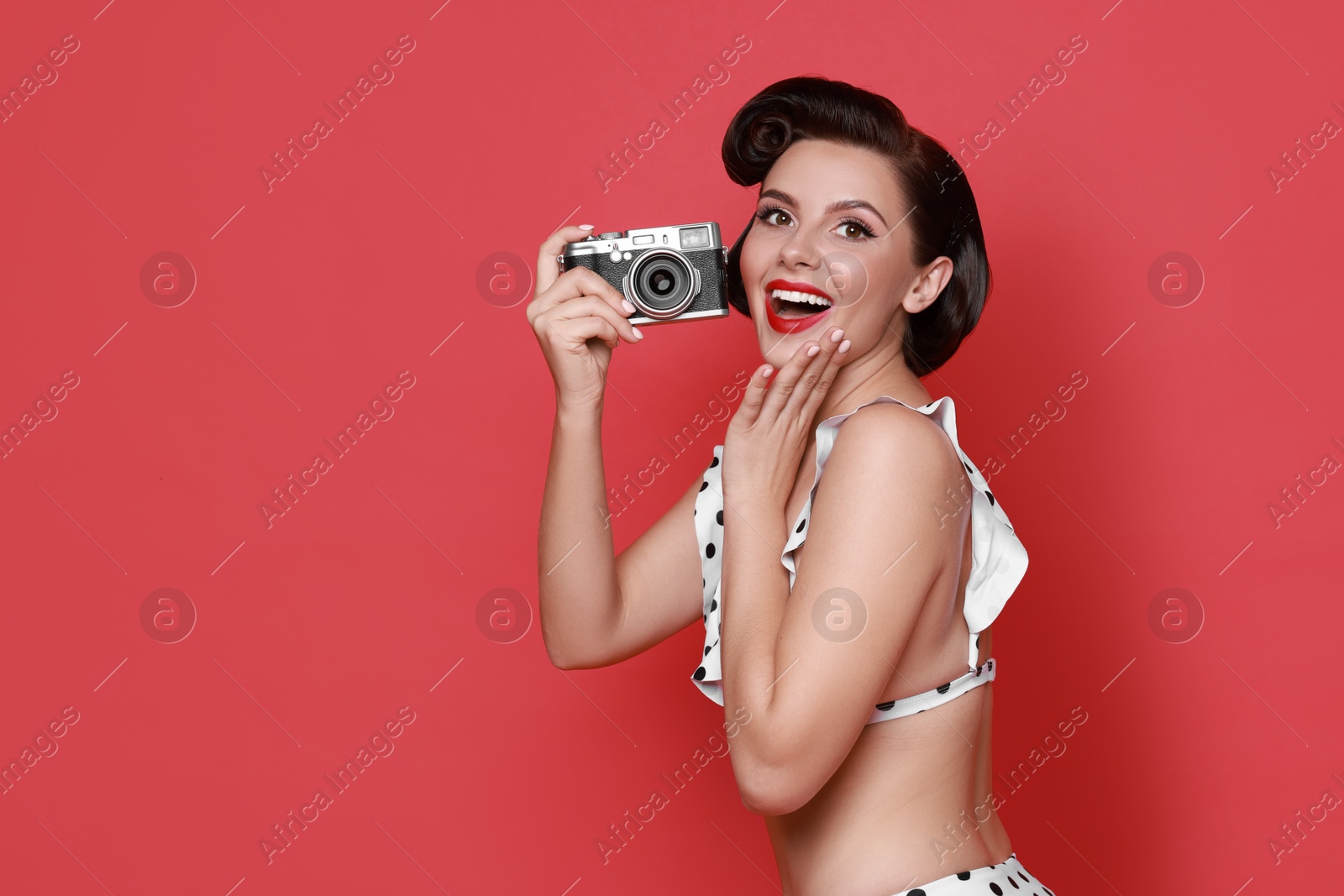 Photo of Pin-up woman in bikini with camera on red background, space for text