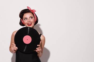 Photo of Pin-up woman with vinyl record on light background, space for text