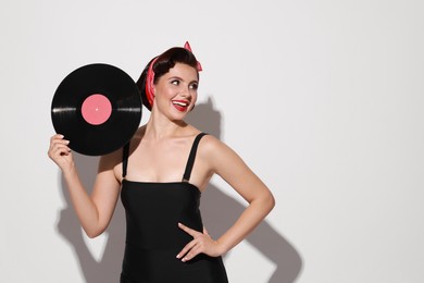 Pin-up woman with vinyl record on light background, space for text