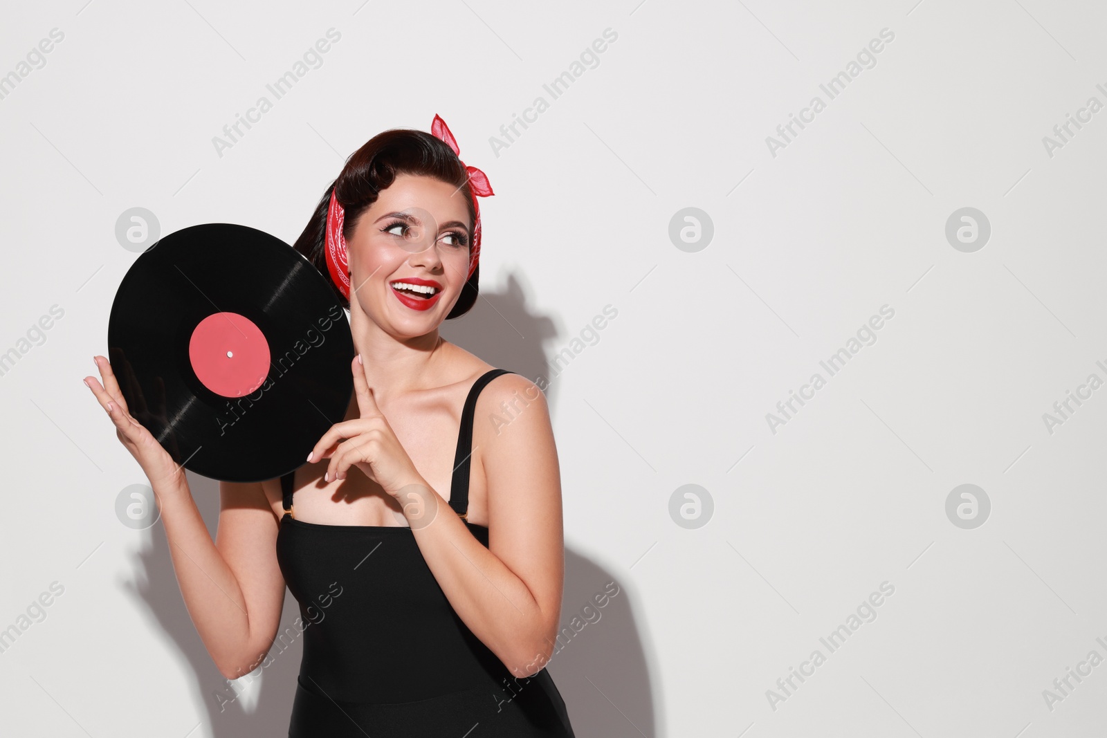 Photo of Pin-up woman with vinyl record on light background, space for text