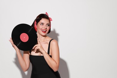 Pin-up woman with vinyl record on light background, space for text