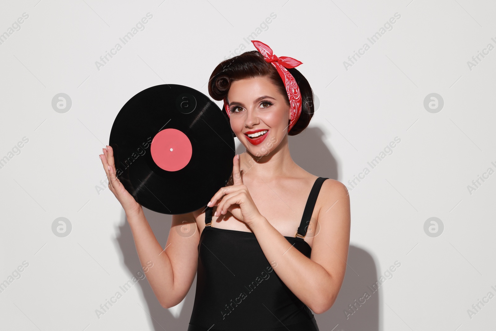 Photo of Pin-up woman with vinyl record on light background