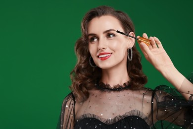 Photo of Smiling woman with makeup brush on green background. Space for text