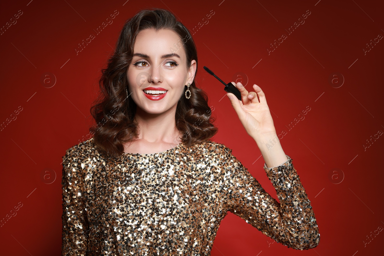 Photo of Smiling woman with makeup brush on red background