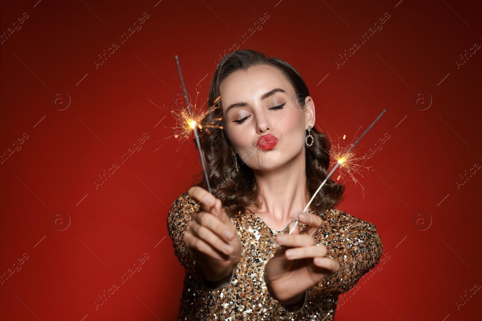 Photo of Woman with sparklers celebrating Christmas on red background