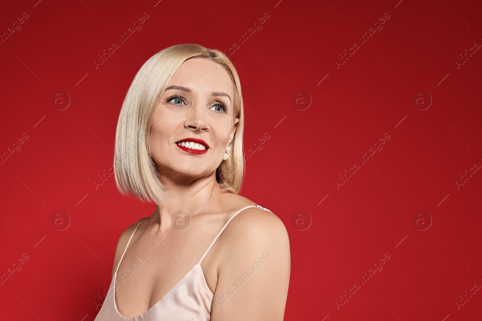 Photo of Smiling woman with perfect makeup on red background. Space for text