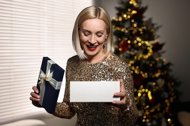 Smiling woman with perfect makeup and Christmas gift at home