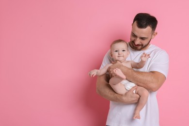 Photo of Father with his cute baby on pink background, space for text