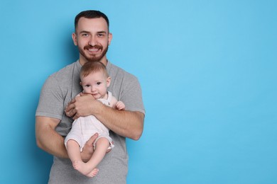 Photo of Father with his cute baby on light blue background, space for text