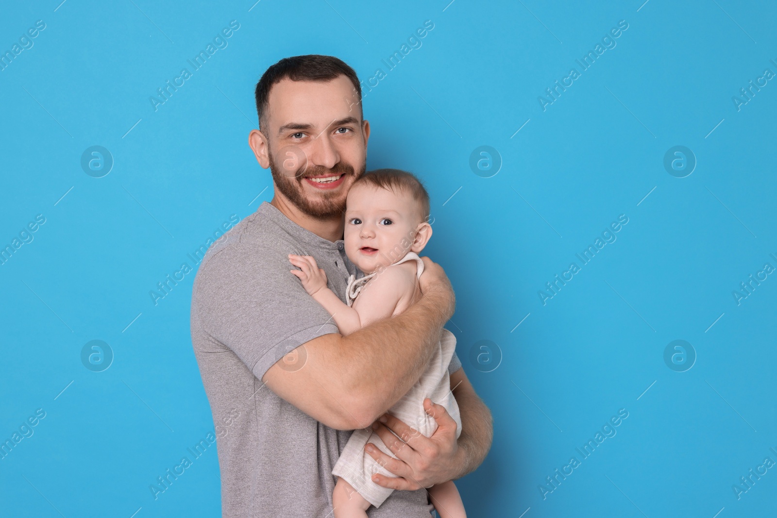 Photo of Father with his cute baby on light blue background