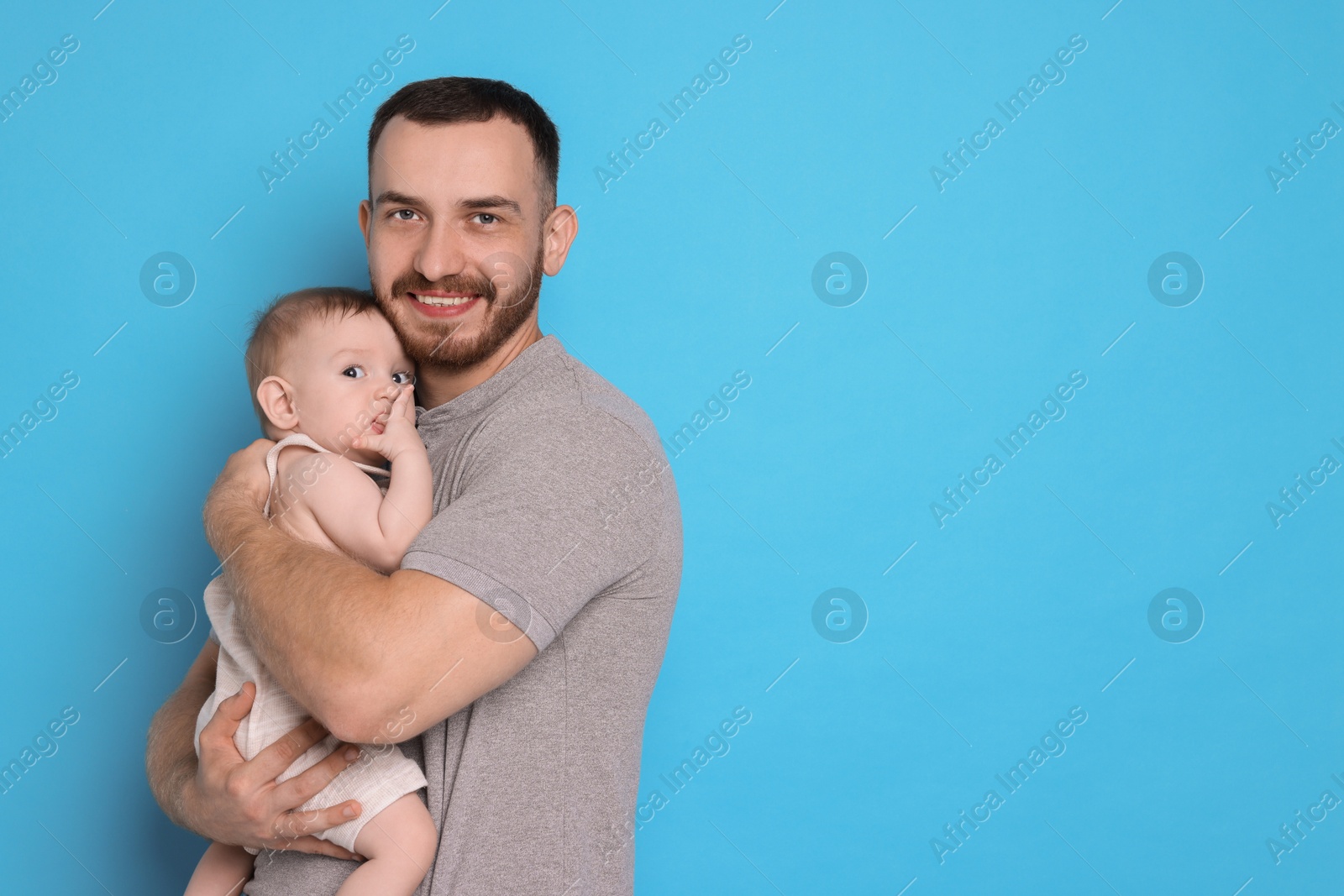 Photo of Father with his cute baby on light blue background, space for text