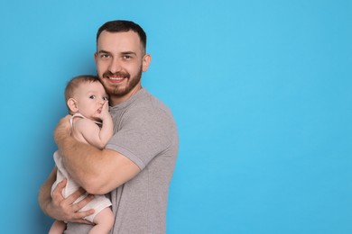 Photo of Father with his cute baby on light blue background, space for text