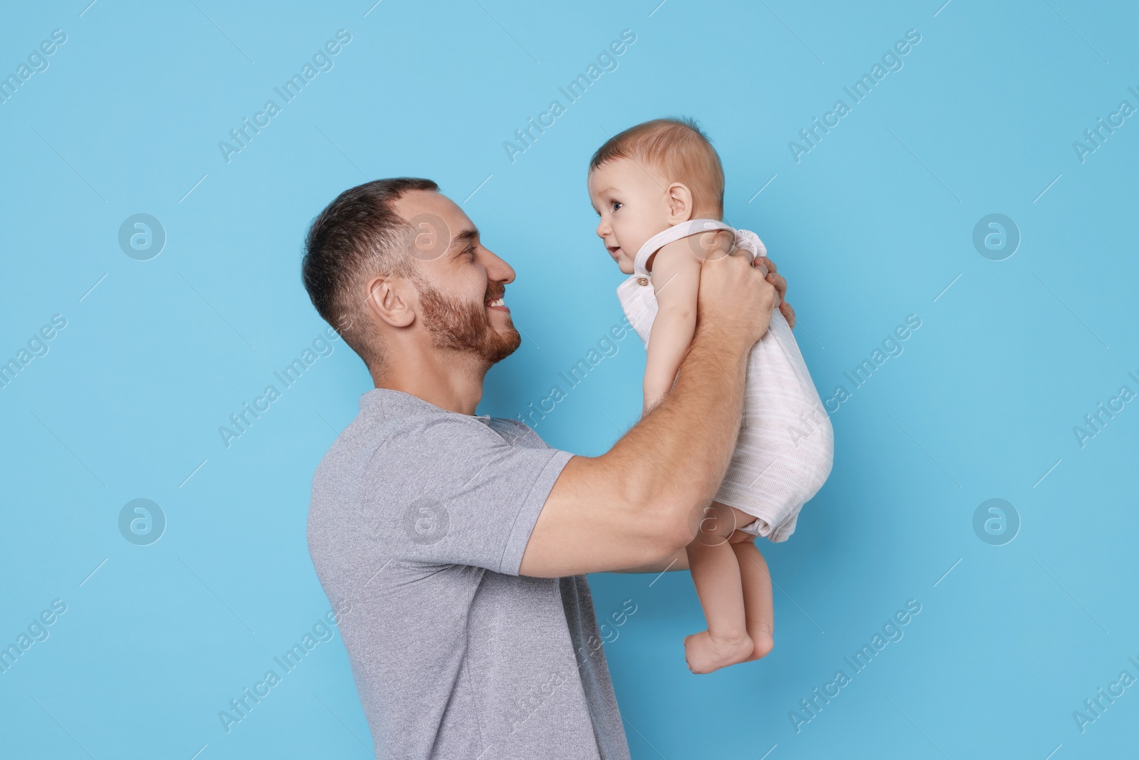 Photo of Father with his cute baby on light blue background